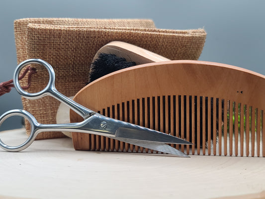 Scissors and a wooden comb on a wooden surface with a gray background
