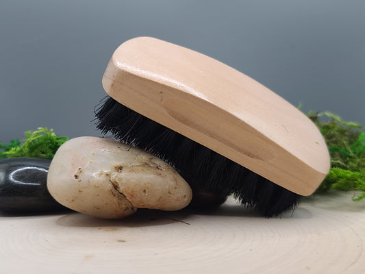 Wooden brush with black bristles on a stone surface with a gray background