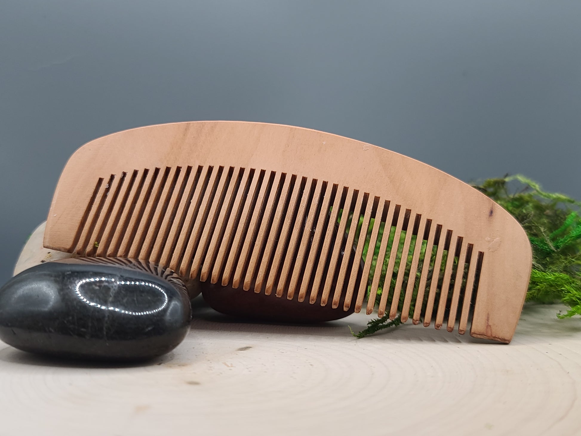 Wooden comb and black stone on a neutral background