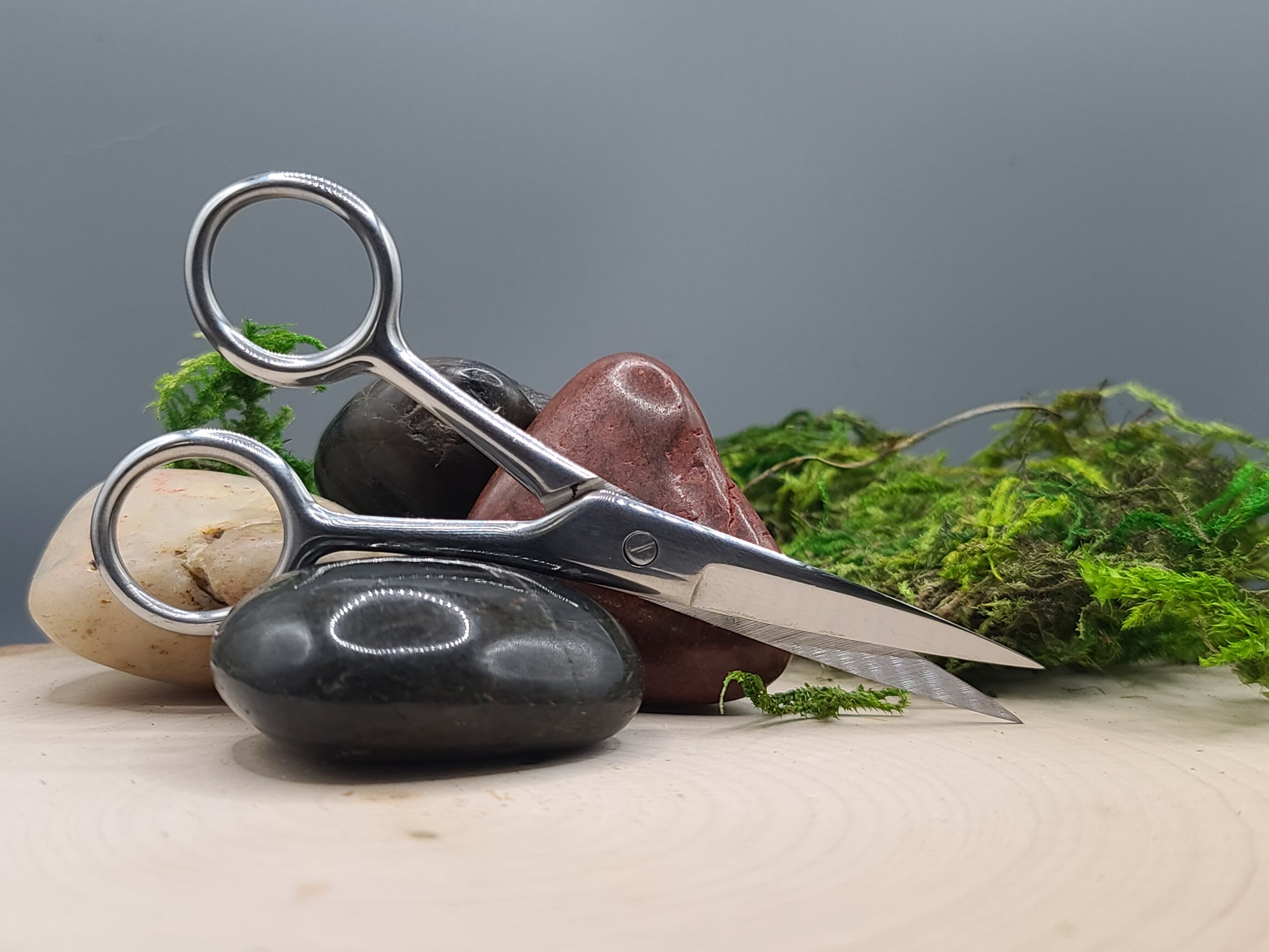 Metal scissors on a rock with a natural background of stones and greenery