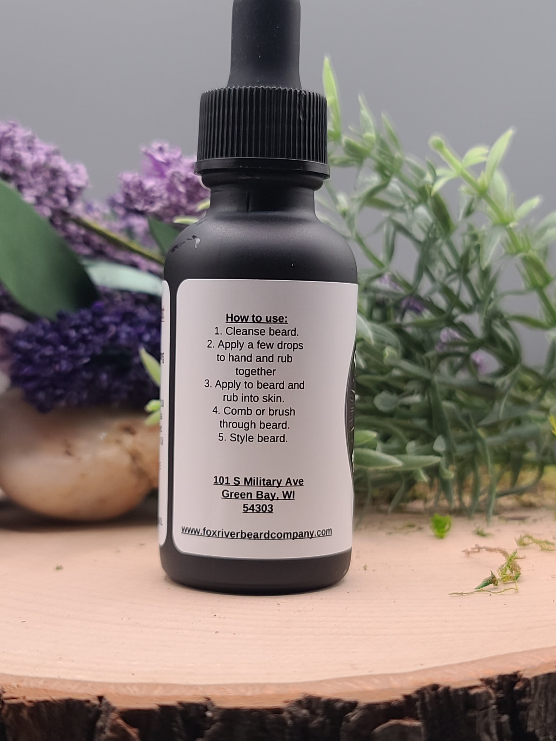 Skincare bottle with dropper on a wooden surface with lavender flowers